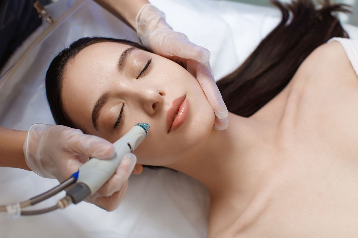 Professional female cosmetologist doing hydrafacial procedure